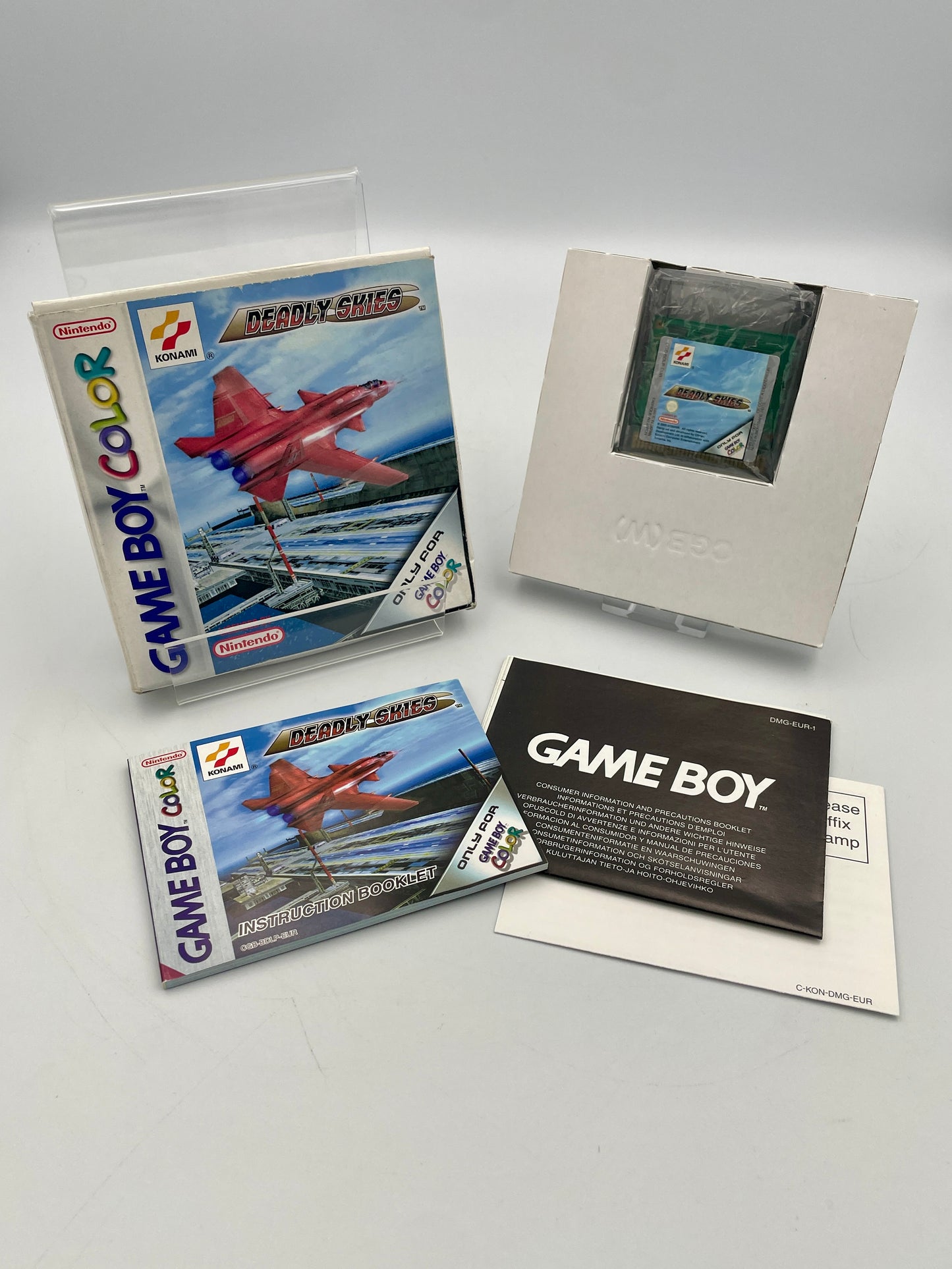 Game Boy Color game cartridge with packaging and manual on a gray background