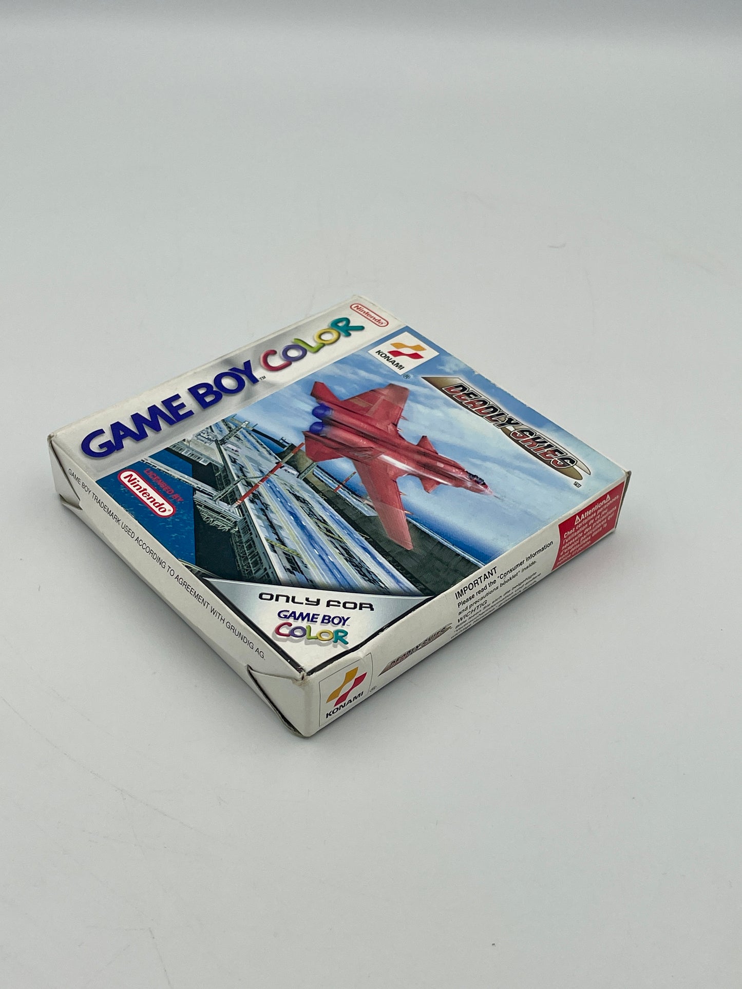 Game Boy Color game cartridge packaging with a red airplane illustration on a gray background