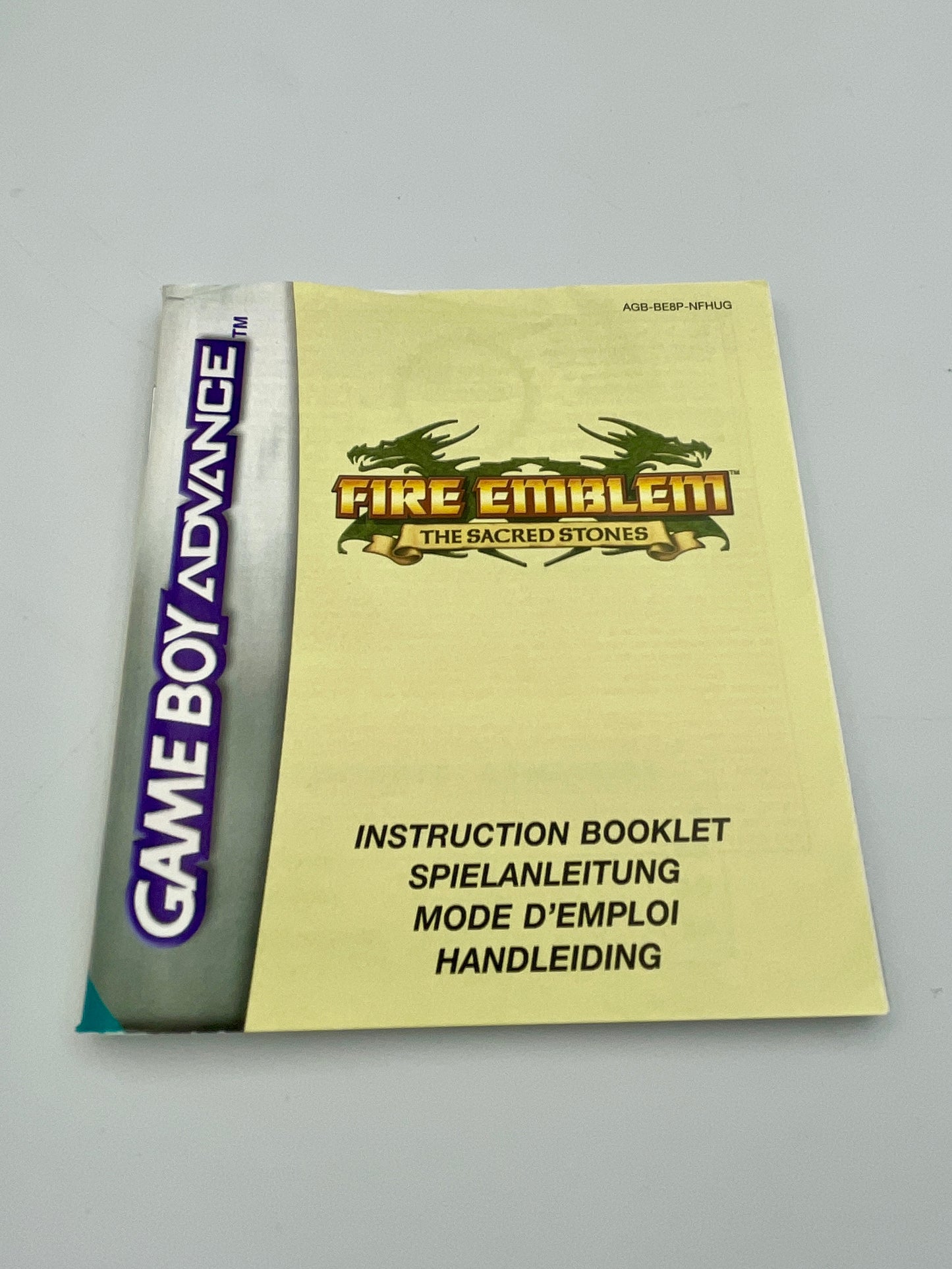 Game Boy Advance game case with 'Fire Emblem: The Sacred Stones' instruction booklet on a gray background