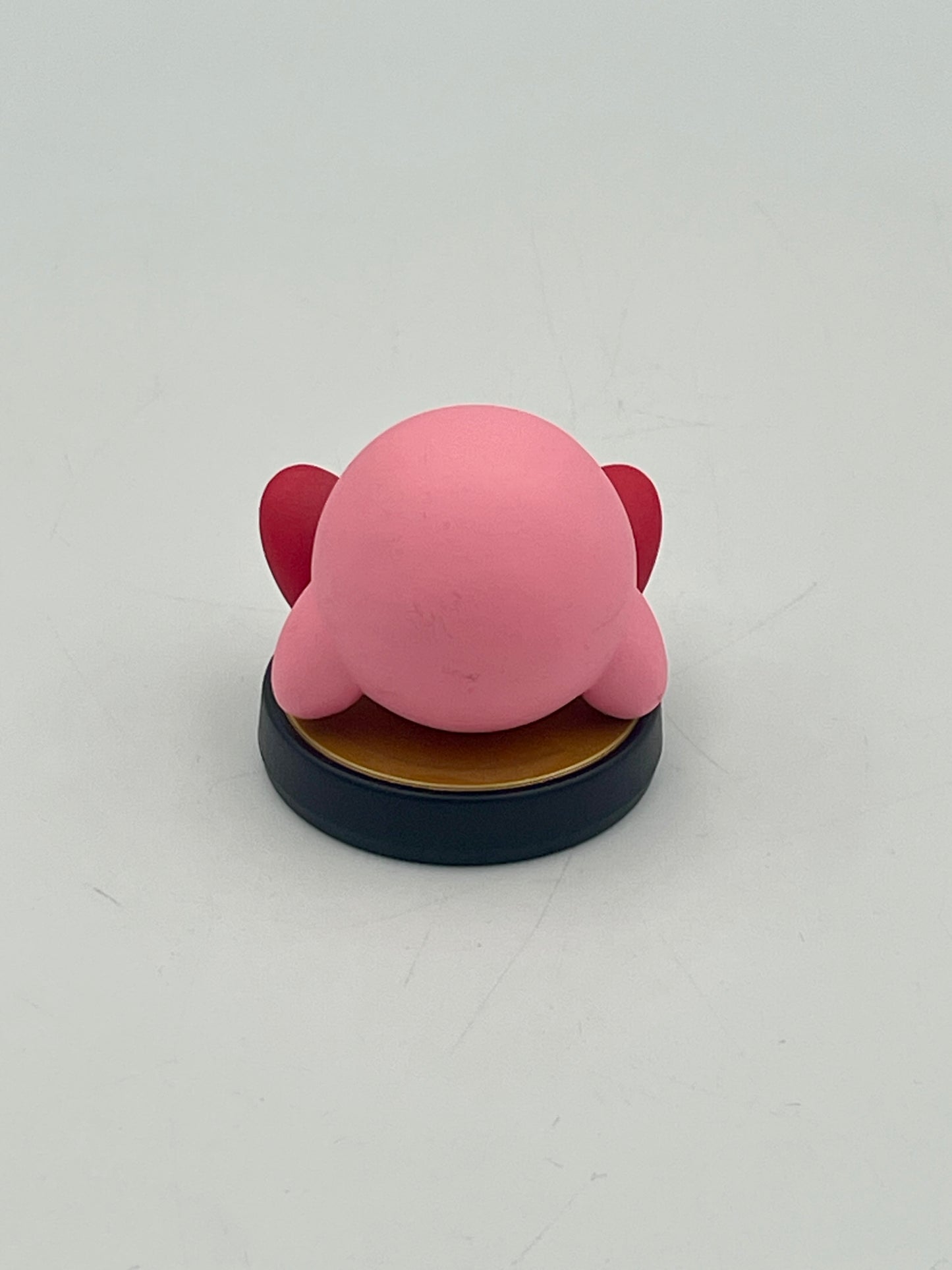 Pink character figurine on a black base against a white background