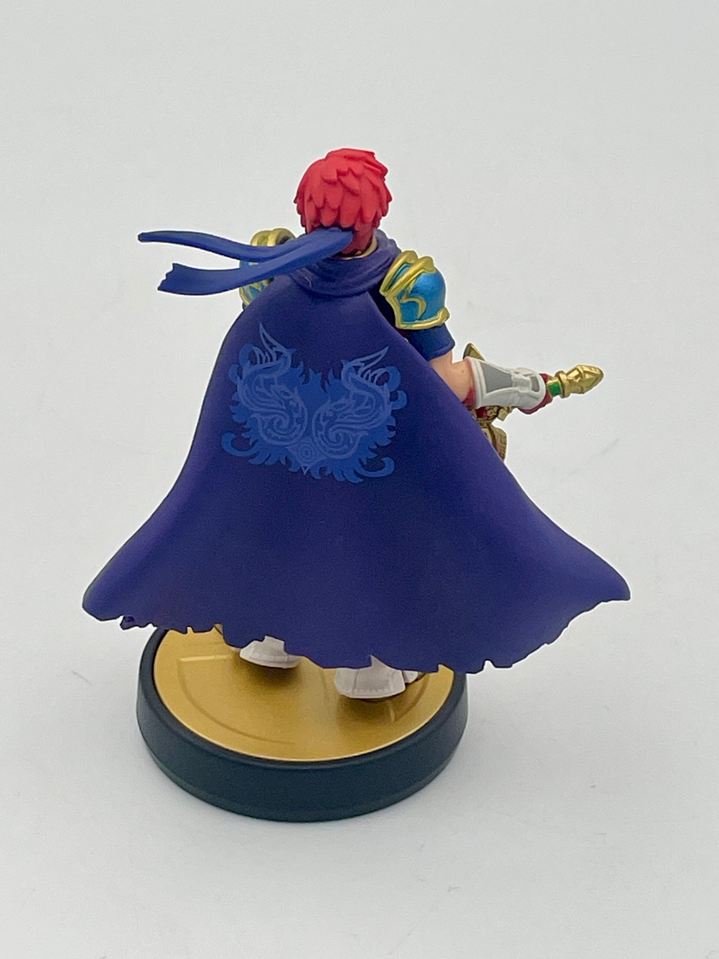 Figurine with a blue cape and red hair on a white background