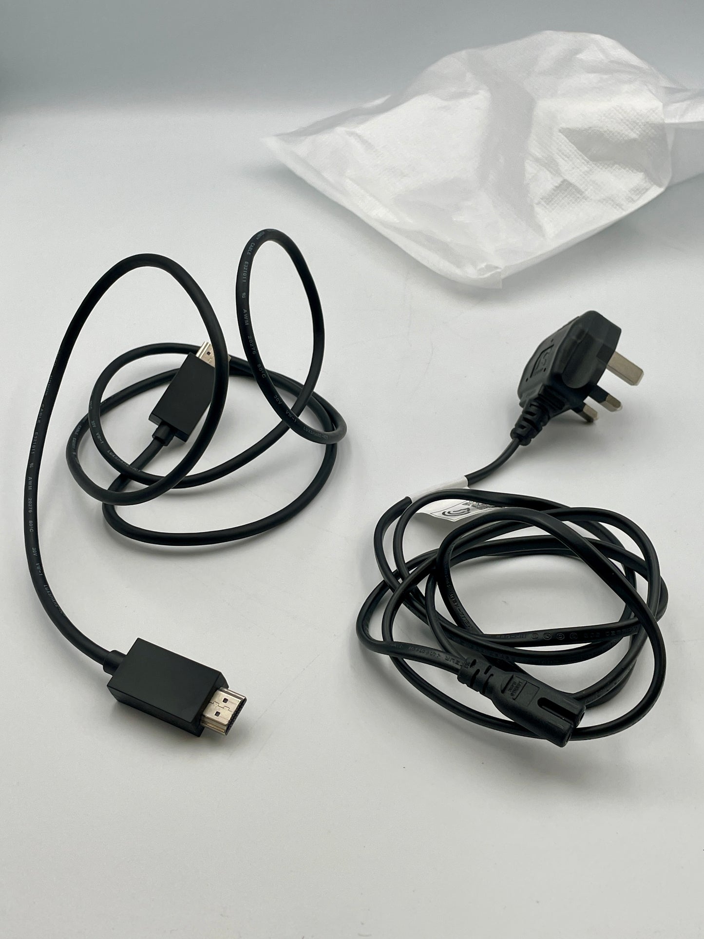 Two black cables on a light gray surface with a white cloth in the background.