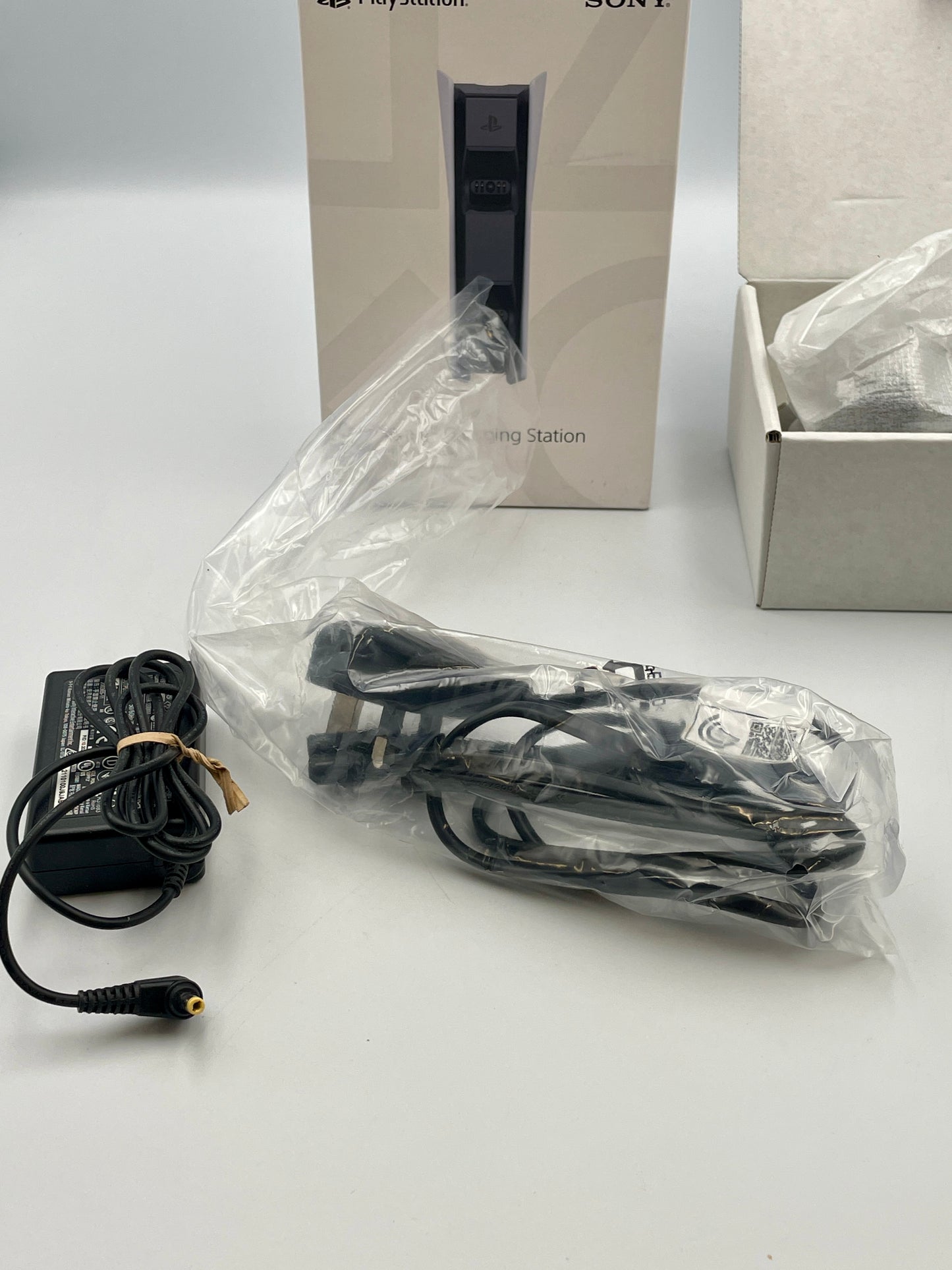 Power adapter and cable with Sony gaming station packaging in the background