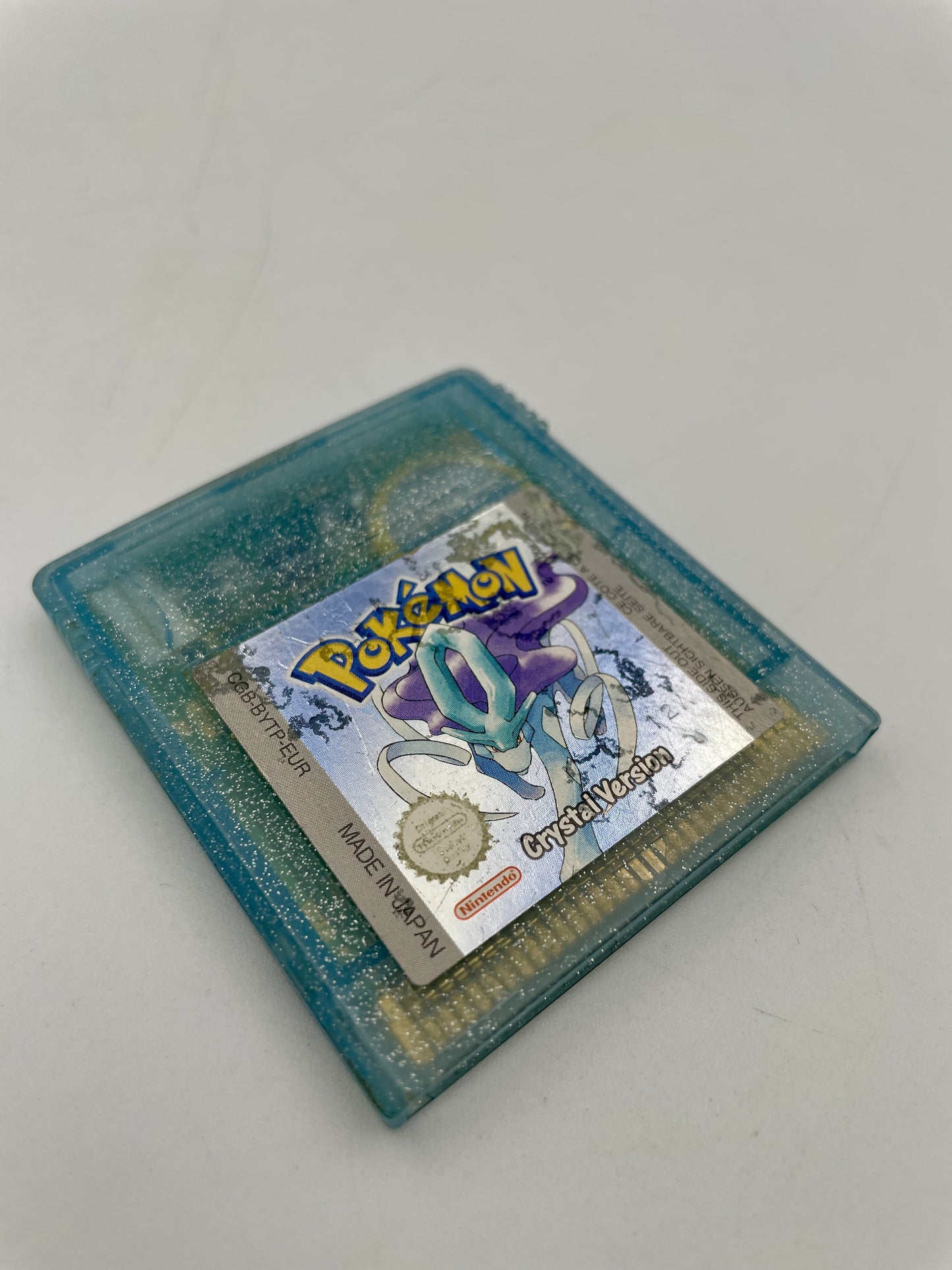 Pokémon game crystal in a blue card holder on a light gray background