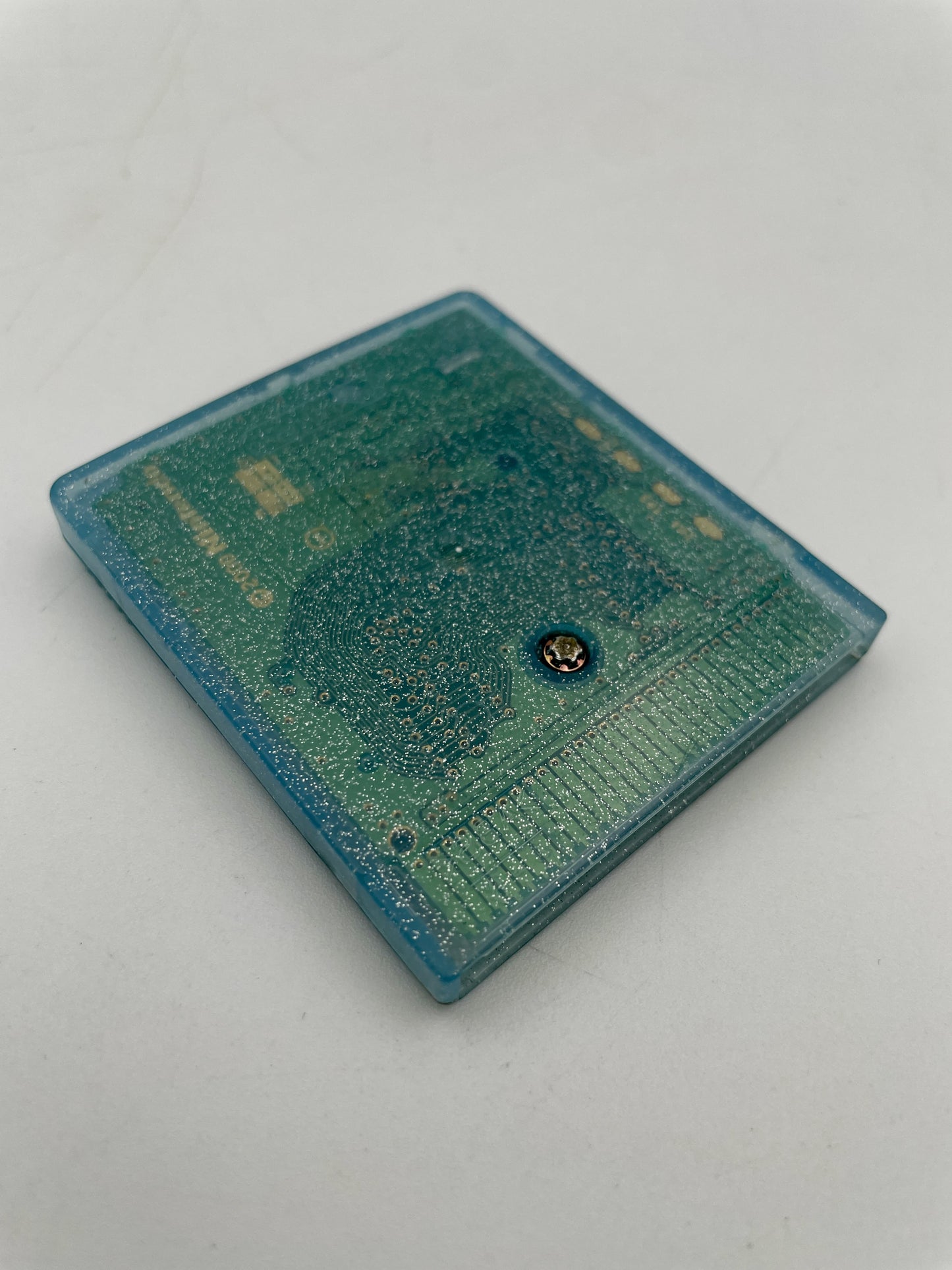 Small blue rectangular object with a metallic component on a light gray background
