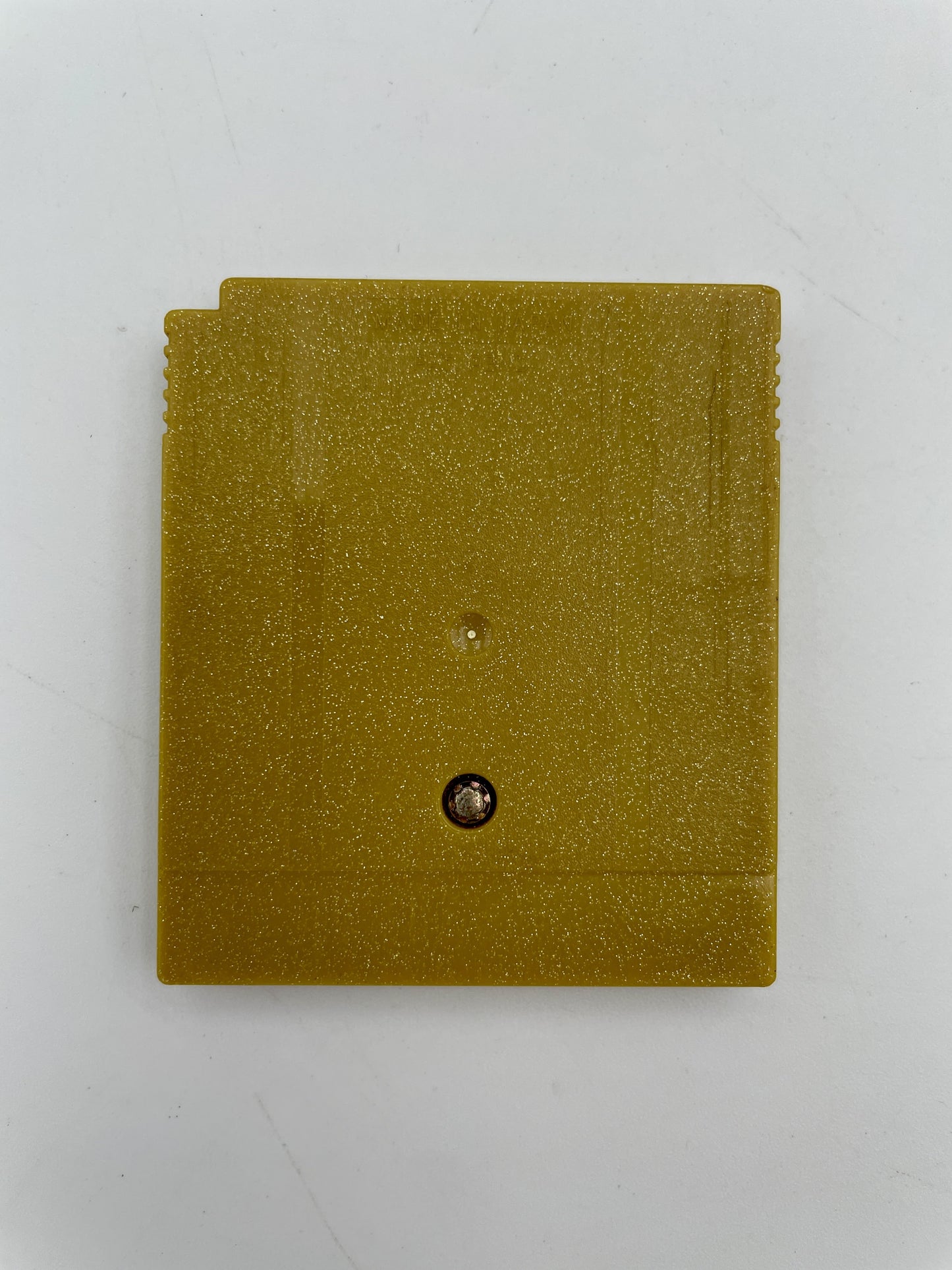 Gold-colored square object with a central screw on a white background