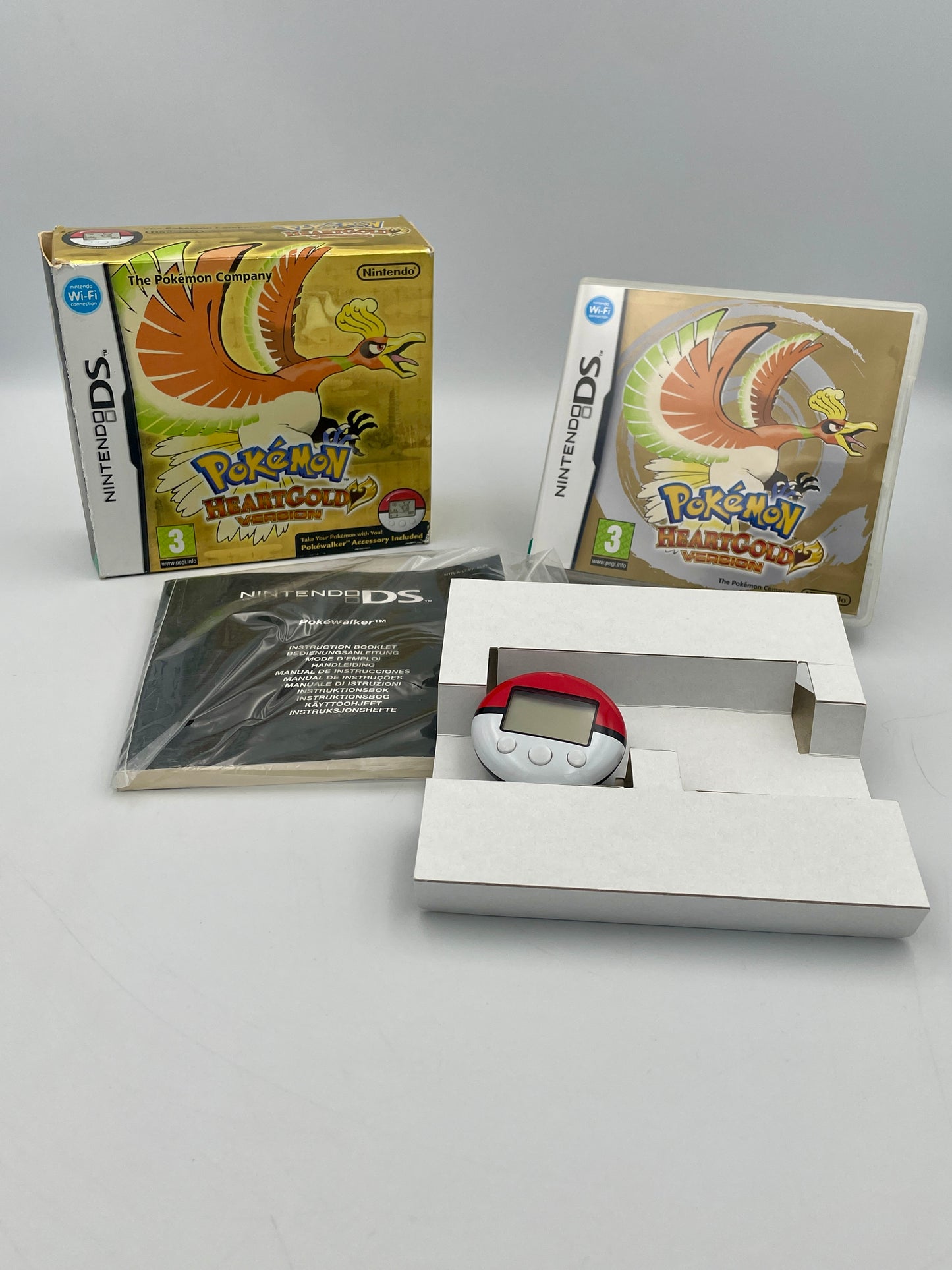 Pokémon HeartGold game for Nintendo DS with packaging and accessories on a gray background