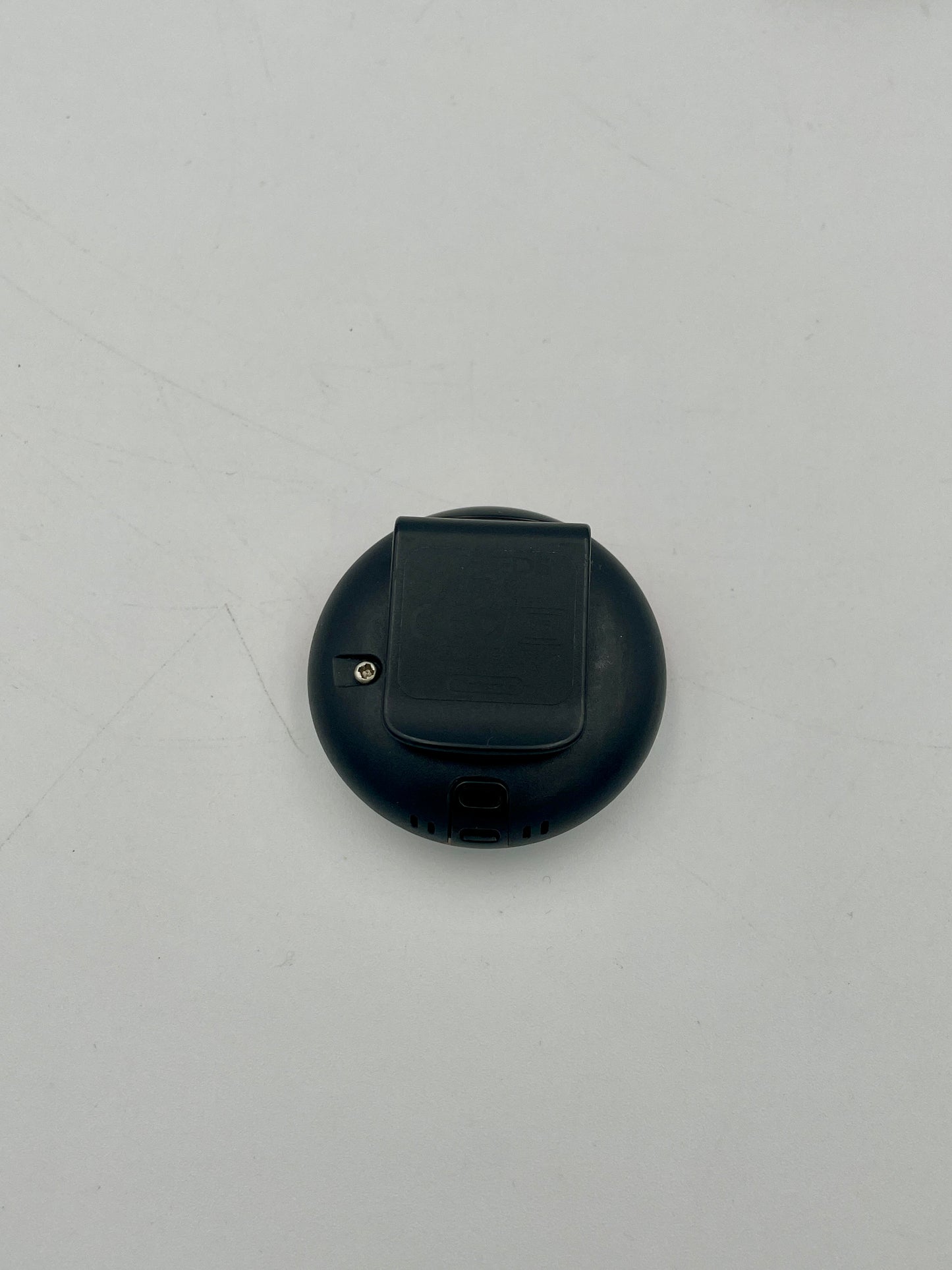 Black circular object with a central component on a light gray background