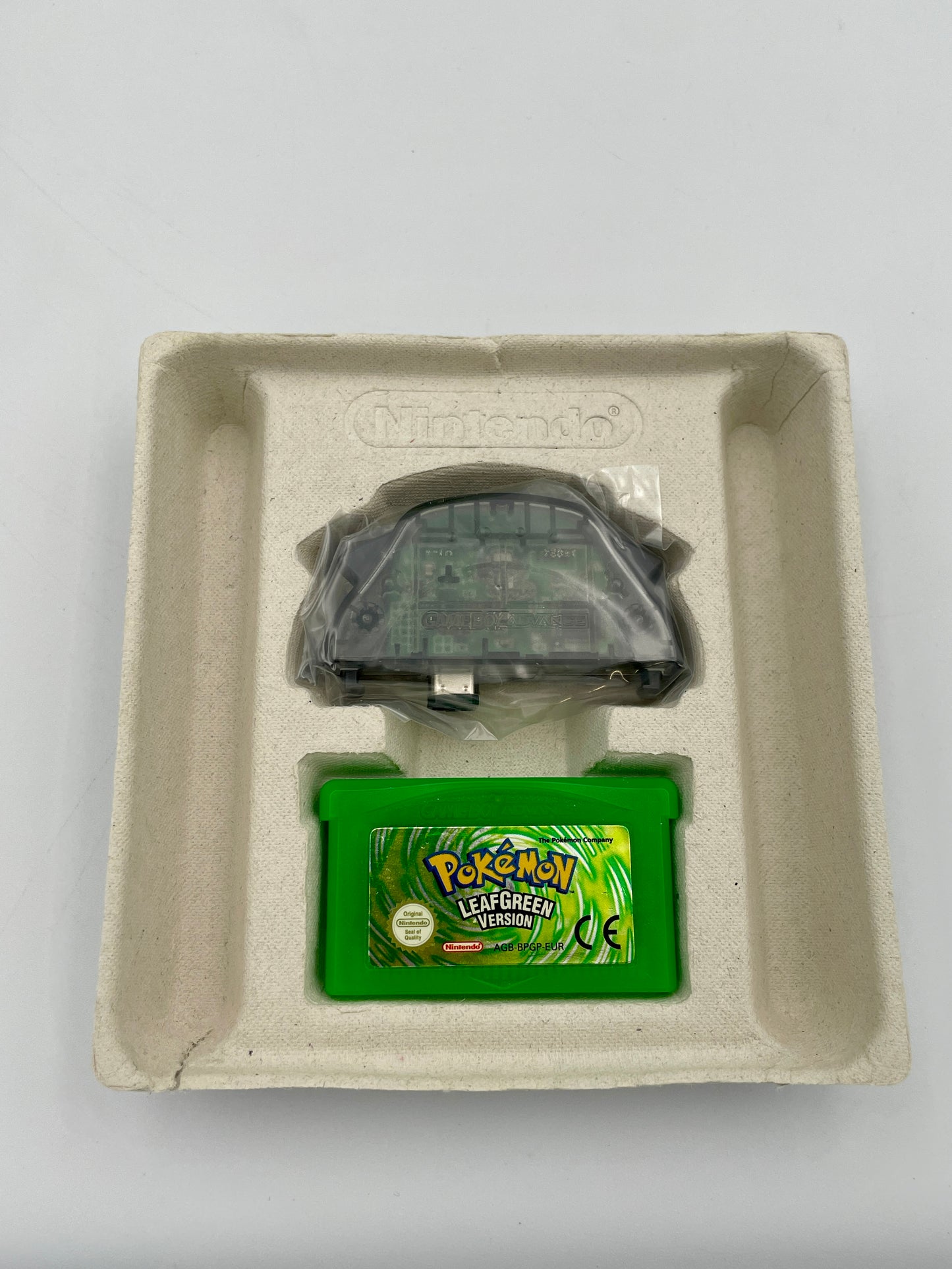 Green Pokémon game cartridge in a cardboard holder with Nintendo branding on a light gray background