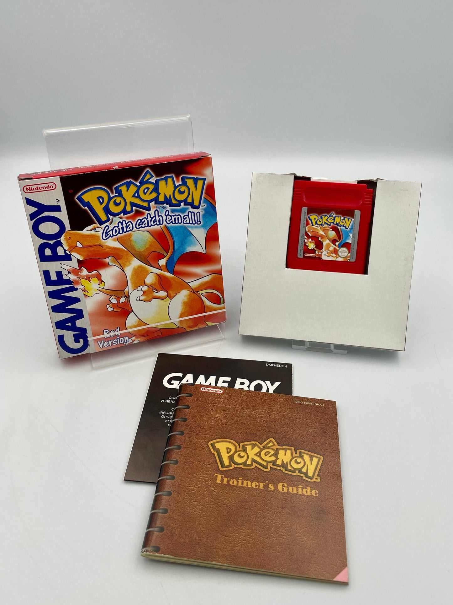 Collection of vintage Game Boy items including a box, manual, and trainer's guide on a white background