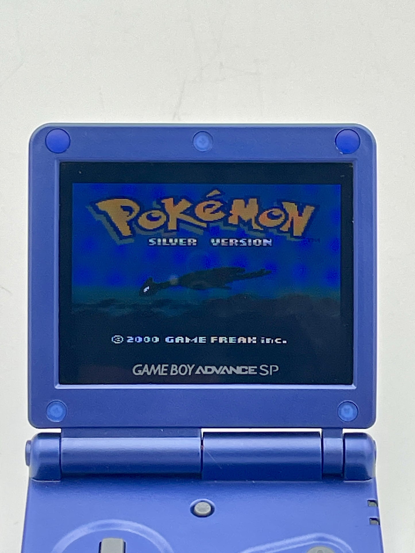Blue Game Boy Advance SP displaying the Pokémon Silver Version title screen on a light gray background.
