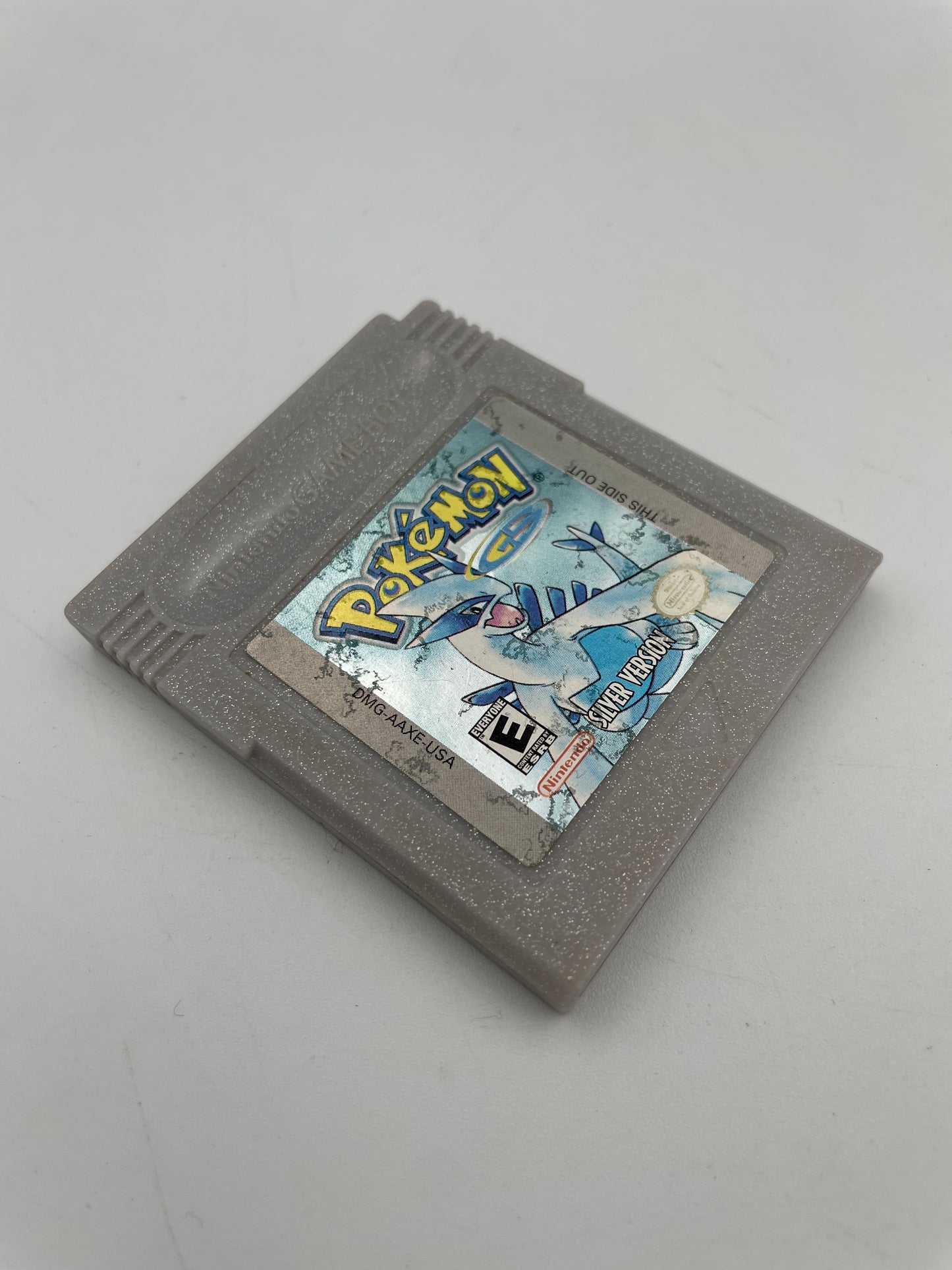 Gray Game Boy cartridge with a colorful label featuring a character and 'Pokémon' text on a light gray background.