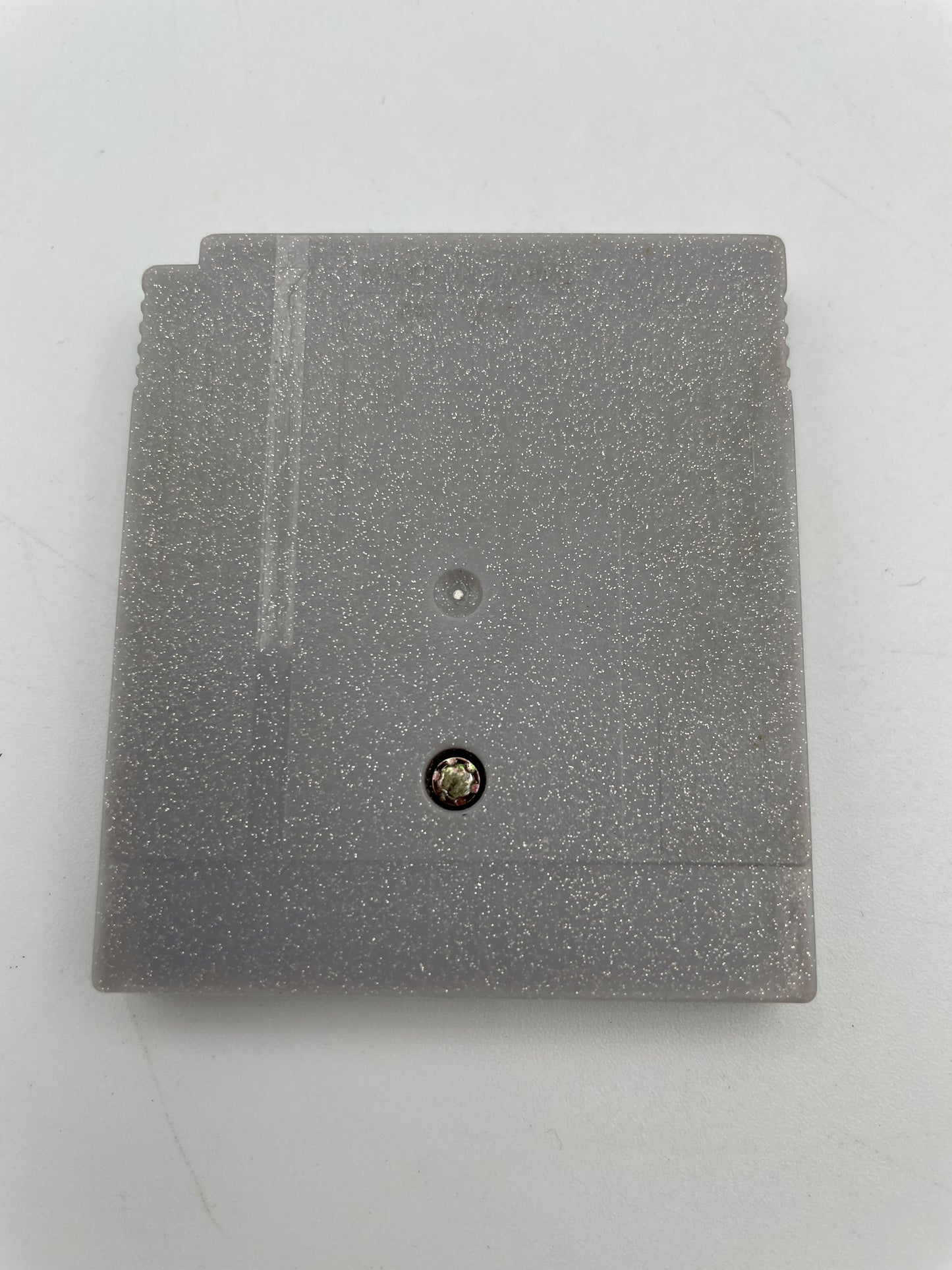 Gray textured square object with a small round component on a light gray background