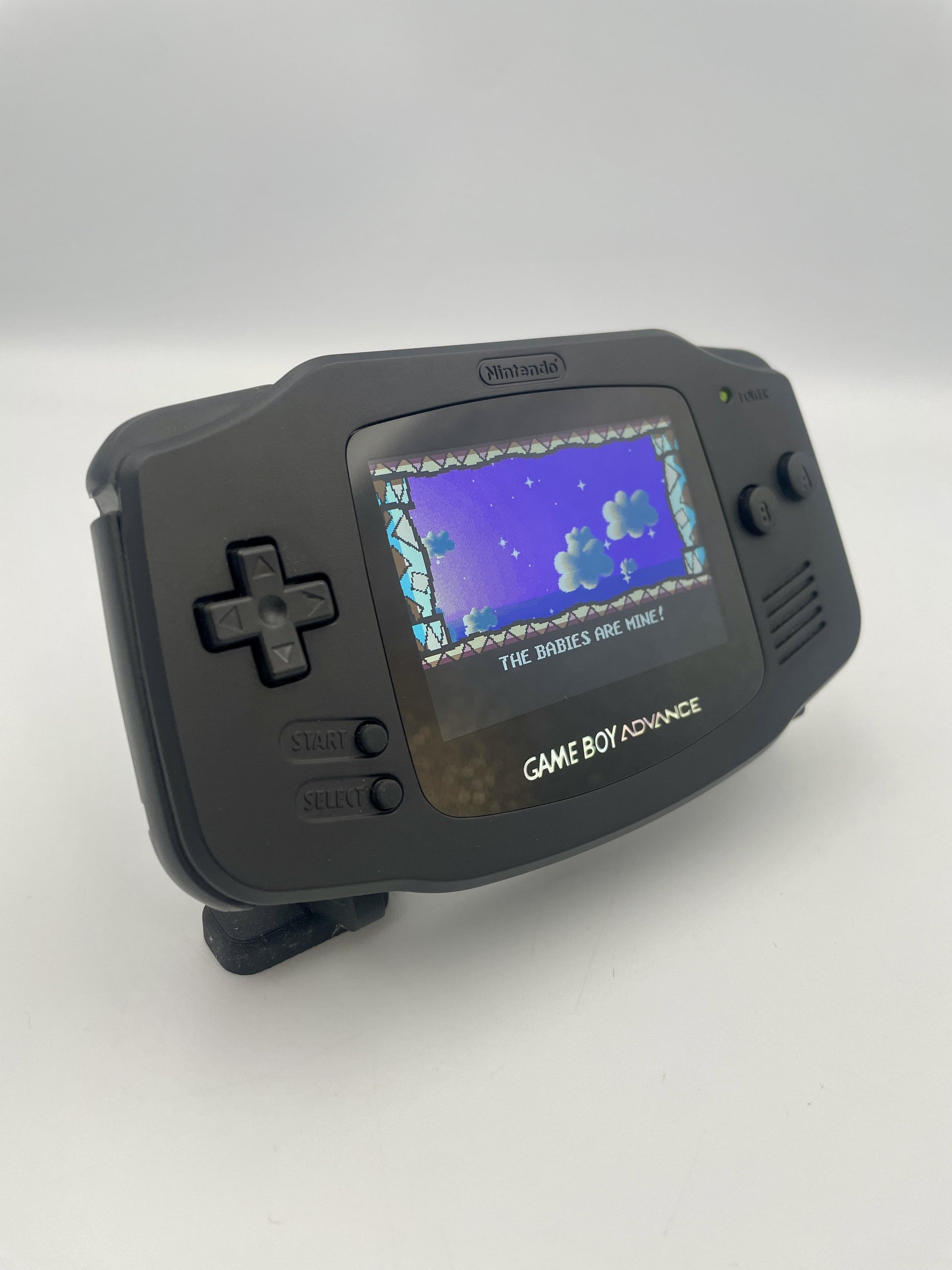 Black Game Boy Advance with a game displayed on the screen against a white background