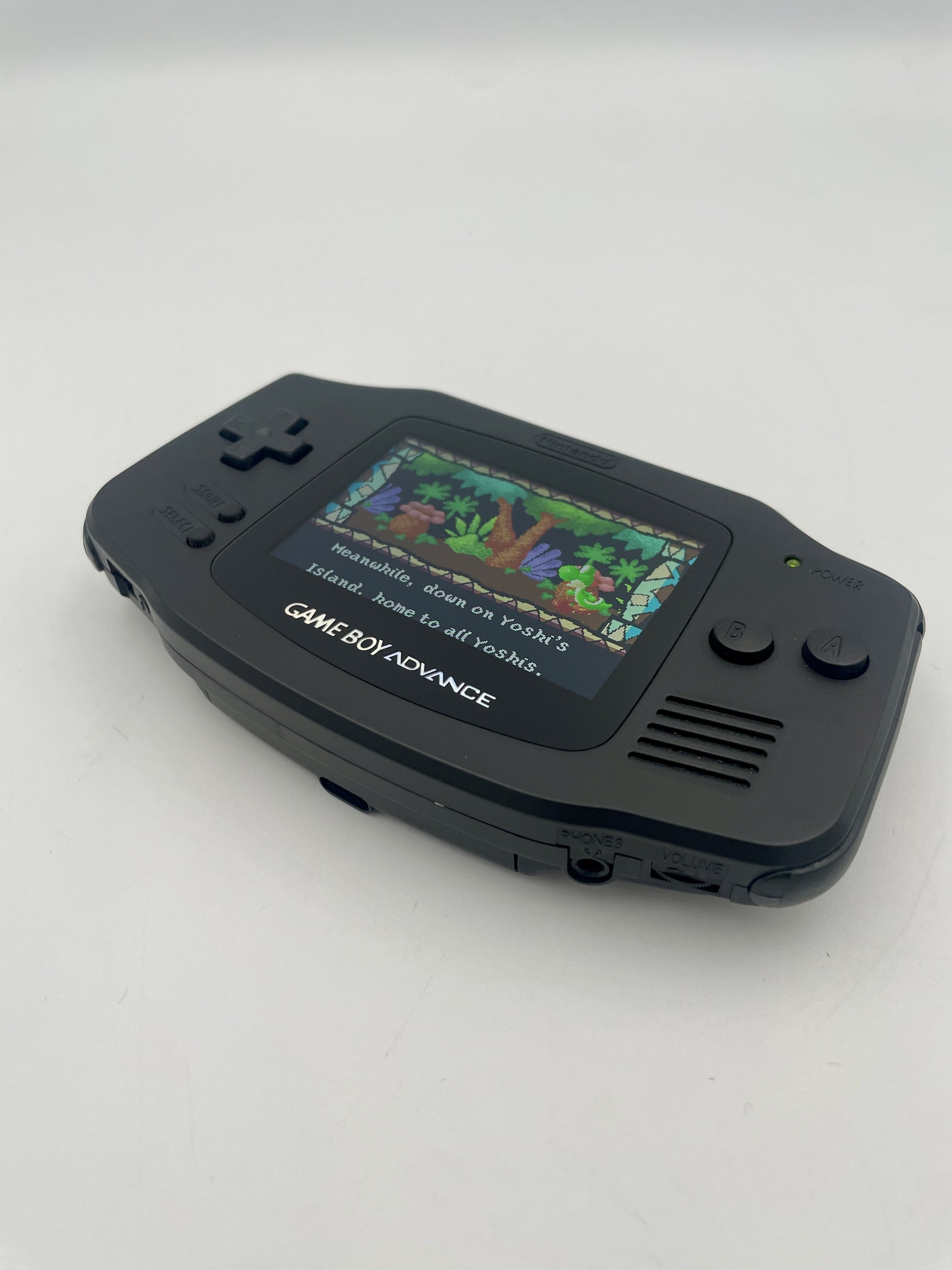 Black Game Boy Advance with a colorful screen displaying a game on a white background
