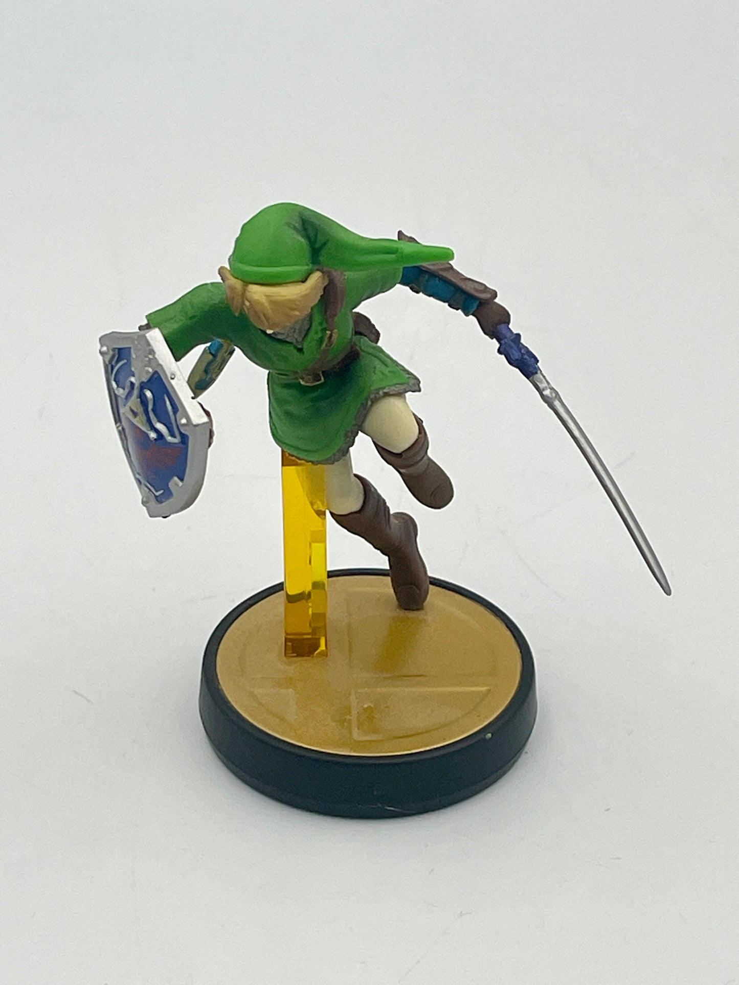 Toy figure of a character in green outfit with sword and shield on a white background