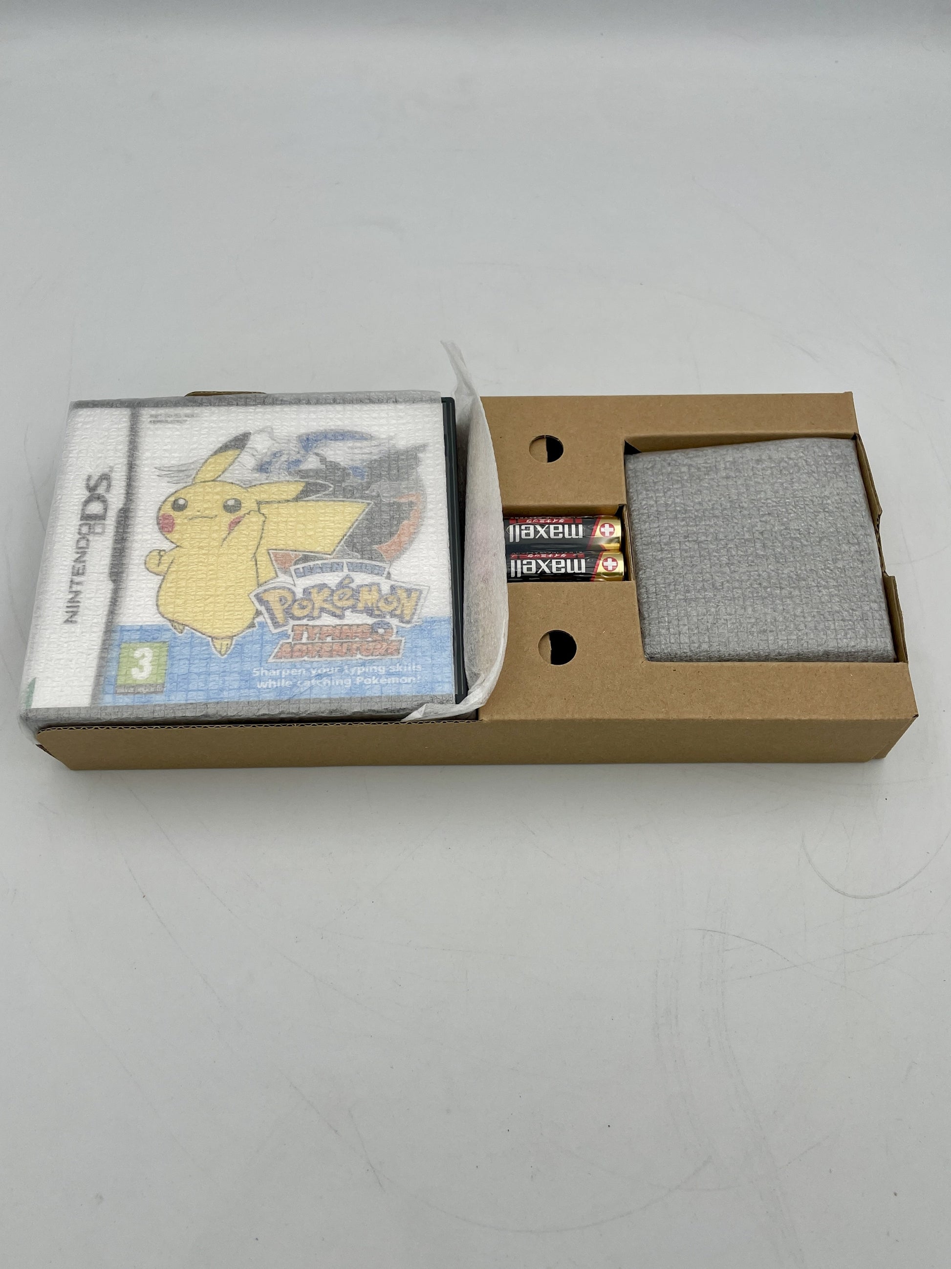 Nintendo DS game case with Pikachu on the cover, placed inside a cardboard box.