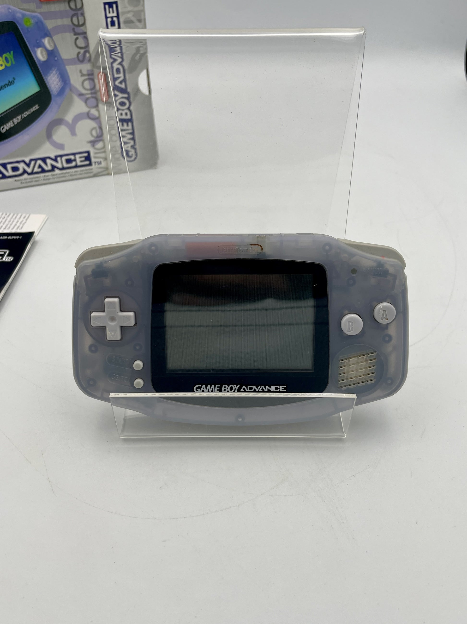 Gray Game Boy Advance console on a white surface with packaging in the background