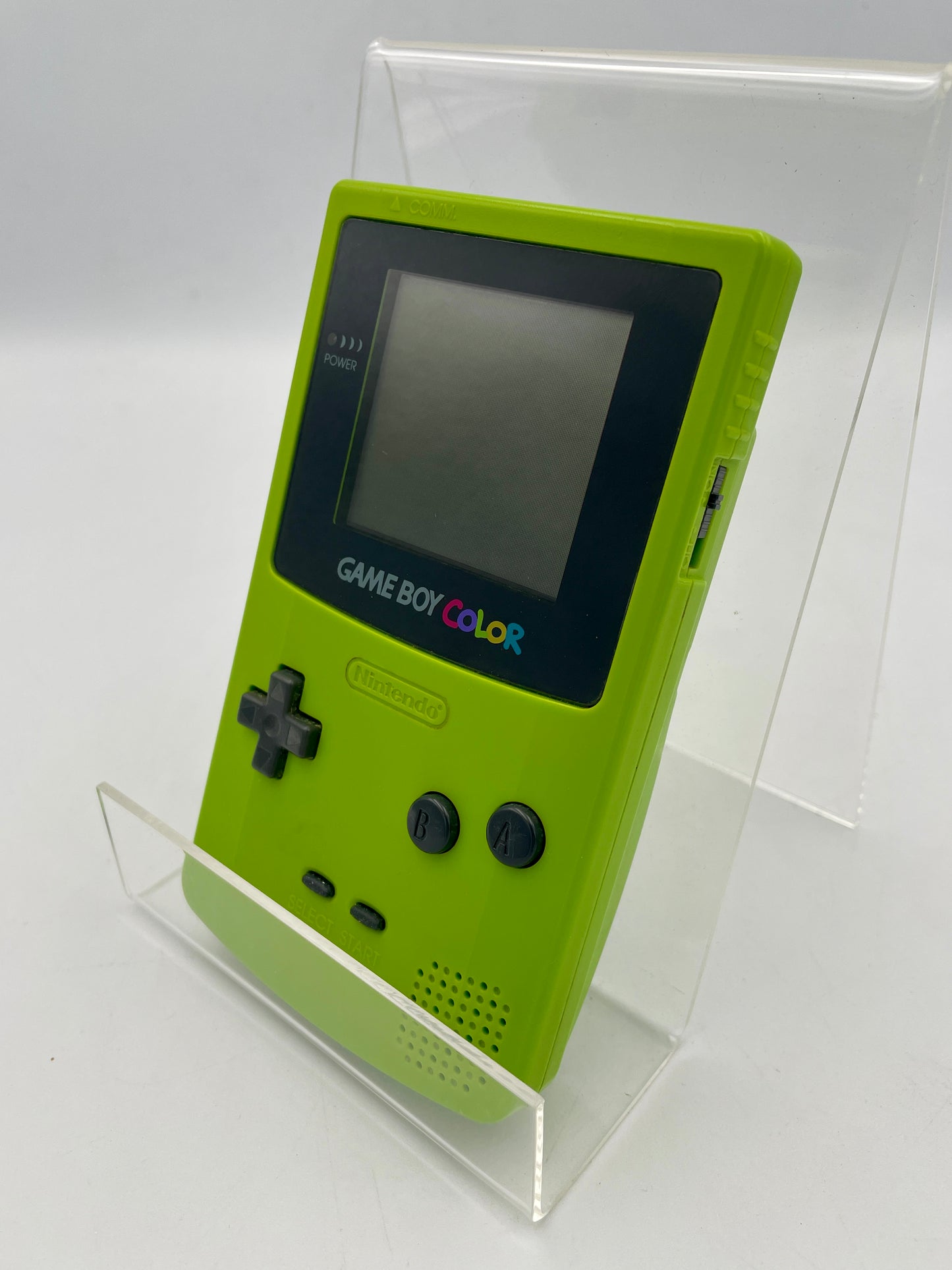 Green Game Boy Color on a clear stand against a white background