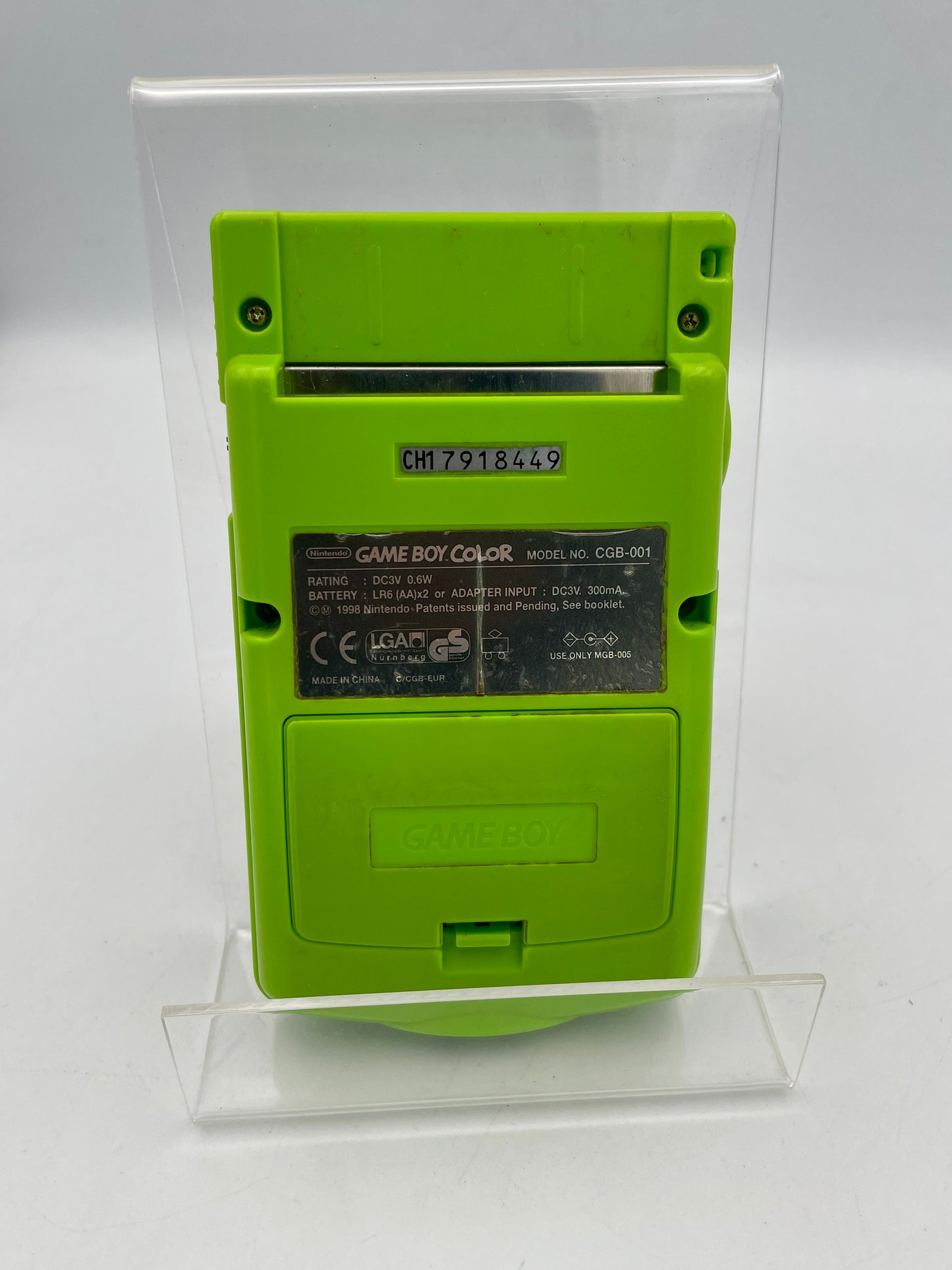 Green Game Boy Color console on a clear stand against a white background
