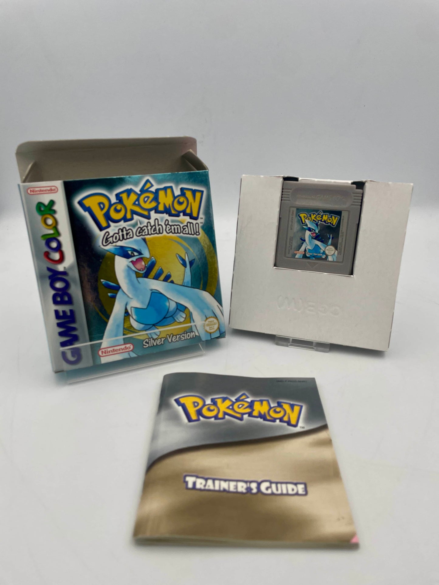 Pokémon Game Boy Color game cartridge with trainer's guide and card on a white background