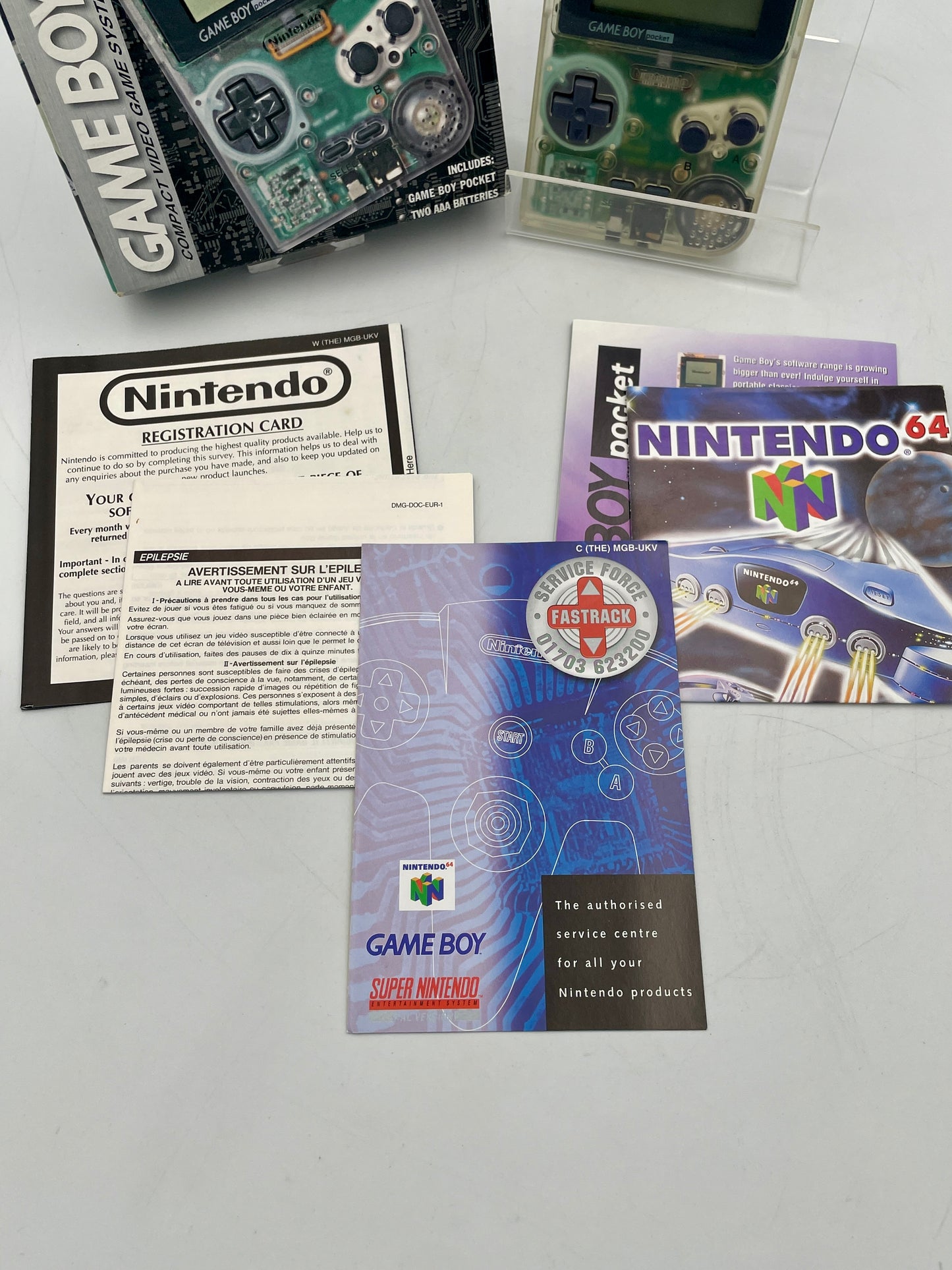 Nintendo Game Boy and 64 items including manuals and packaging on a gray surface