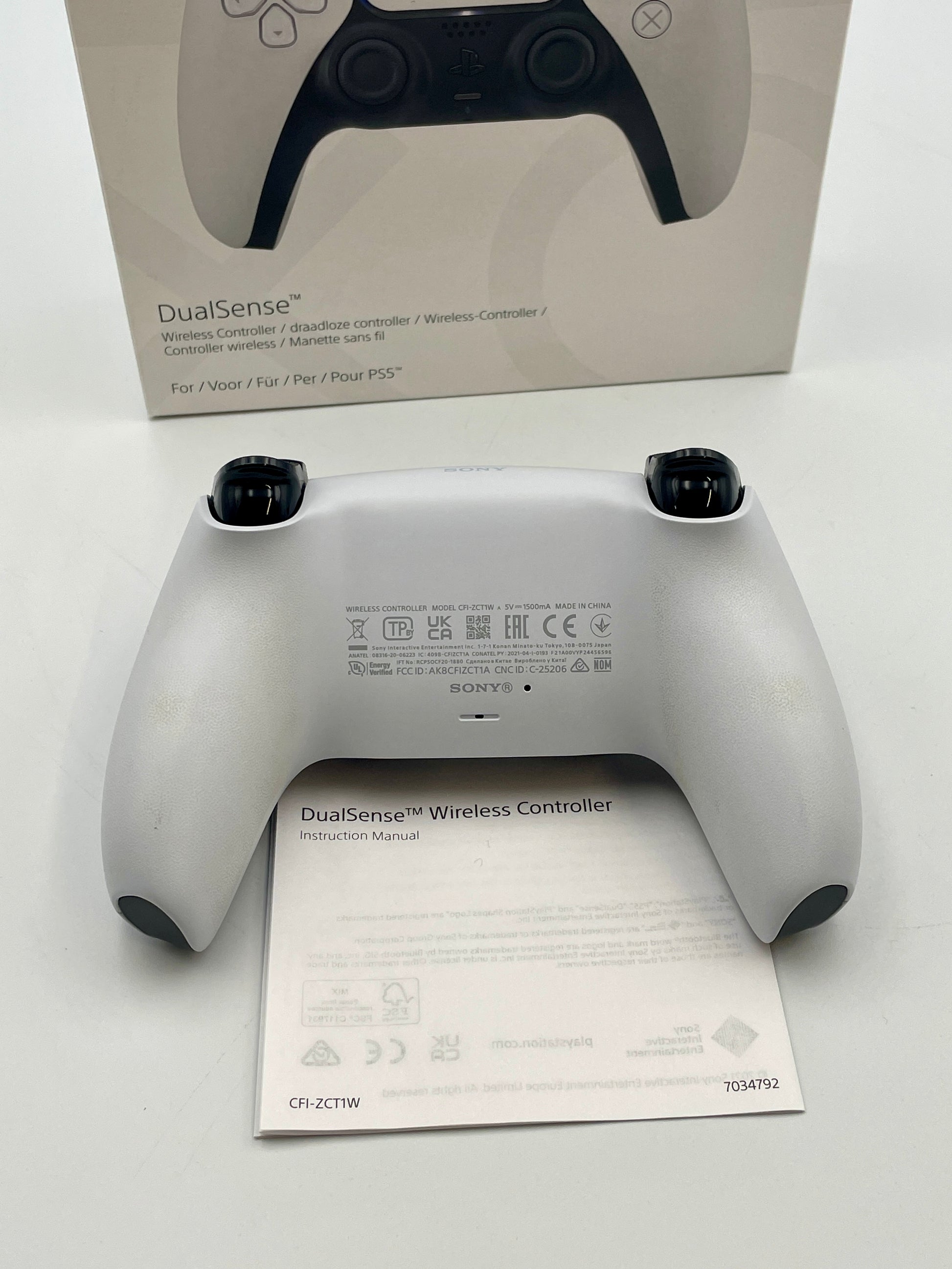 Sony DualSense wireless controller on a white background with packaging in the background