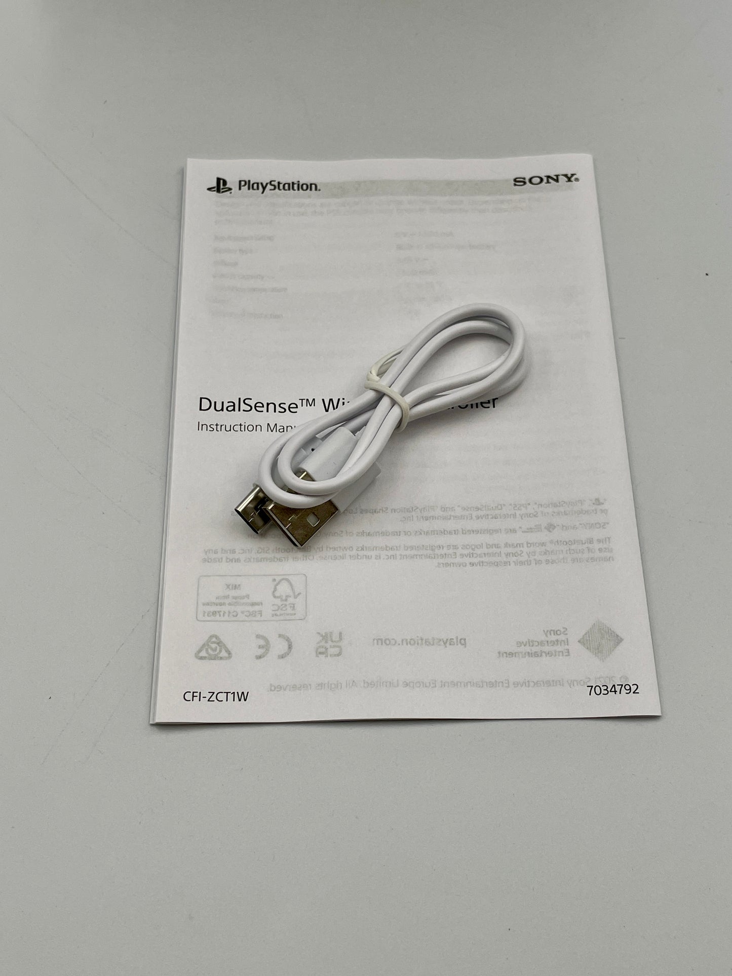 White USB cable on a PlayStation DualSense wireless controller instruction manual
