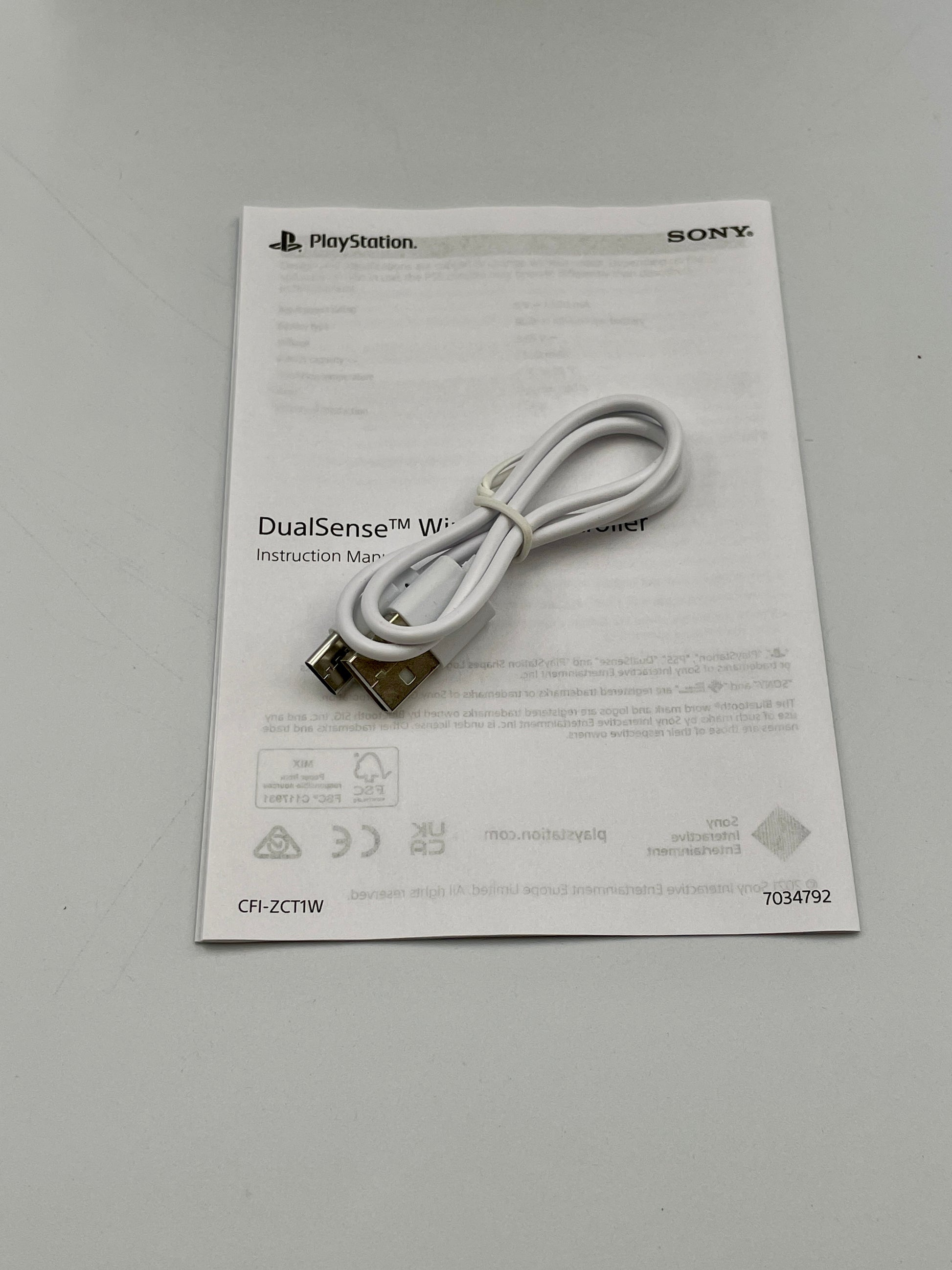 White USB cable on a PlayStation DualSense wireless controller instruction manual