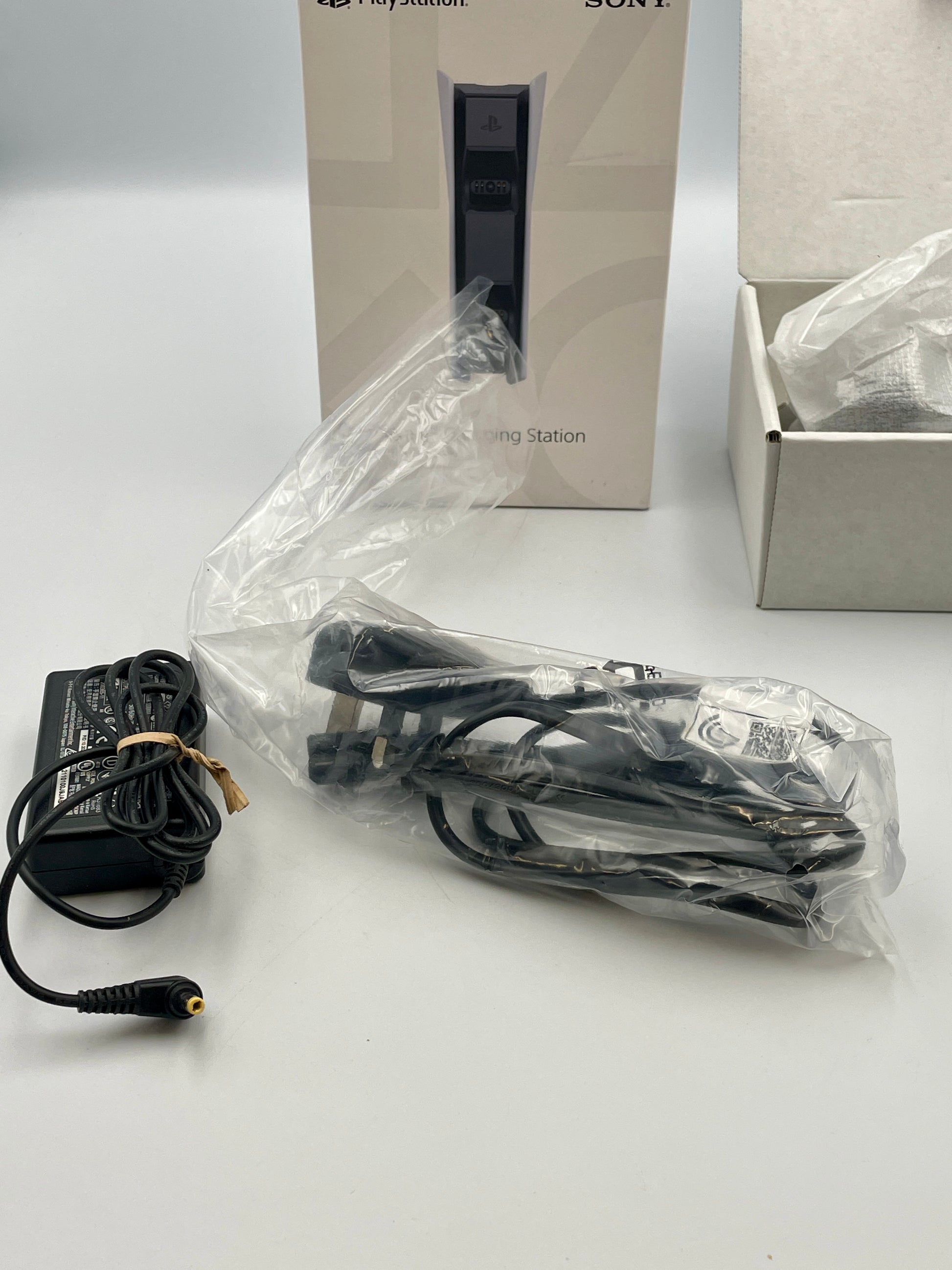 Power adapter and cable with Sony gaming station packaging in the background