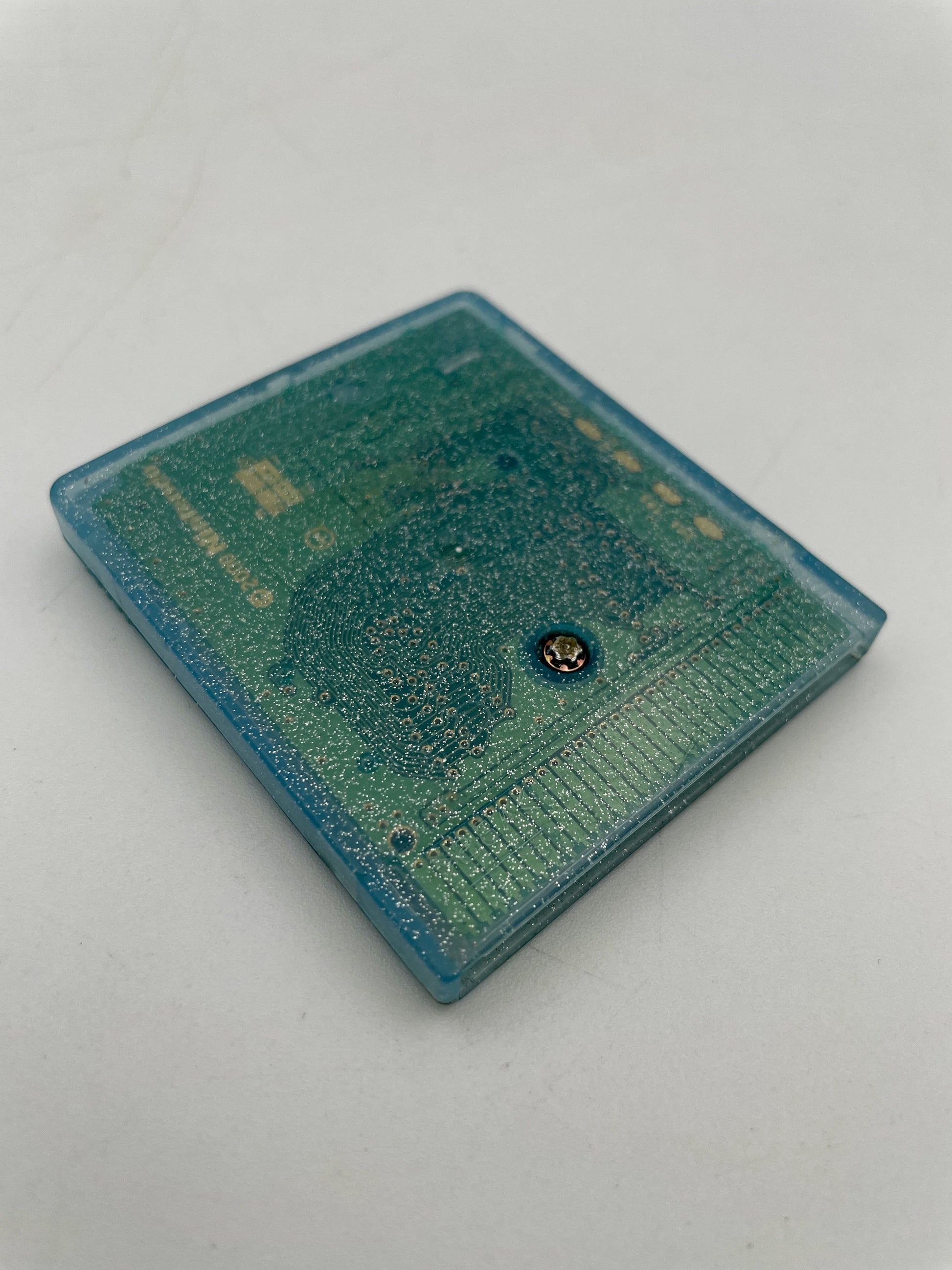 Small blue rectangular object with a metallic component on a light gray background