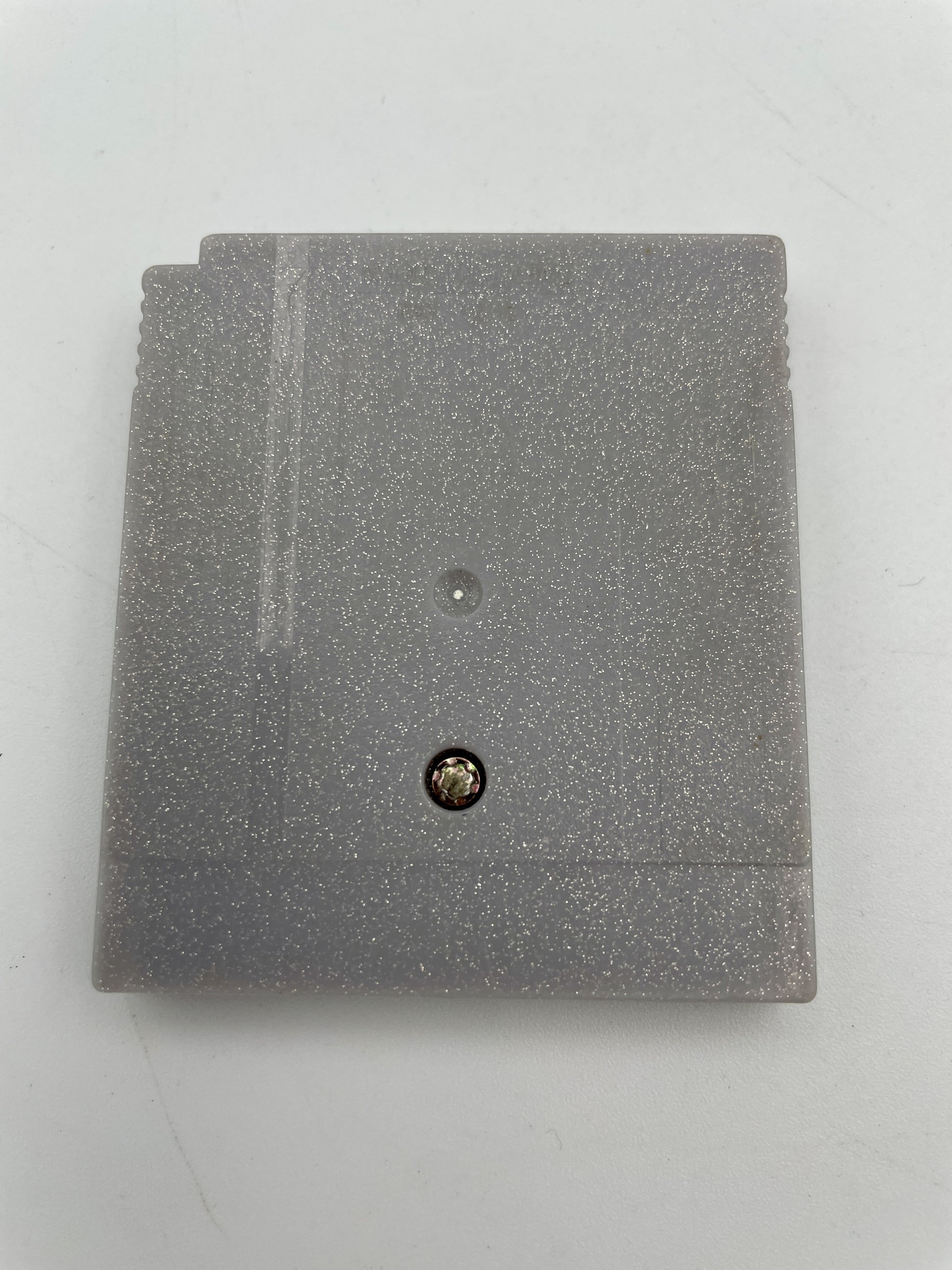 Gray textured square object with a small round component on a light gray background