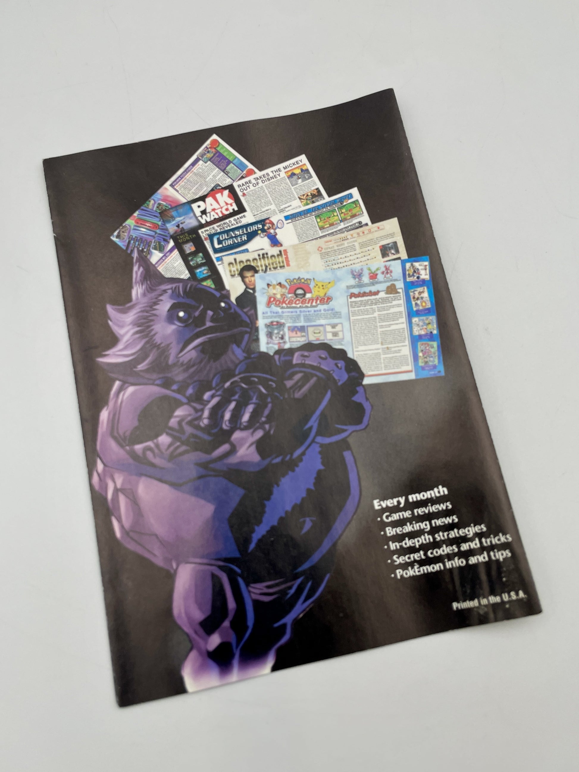 Magazine cover with a purple creature illustration on a gray background